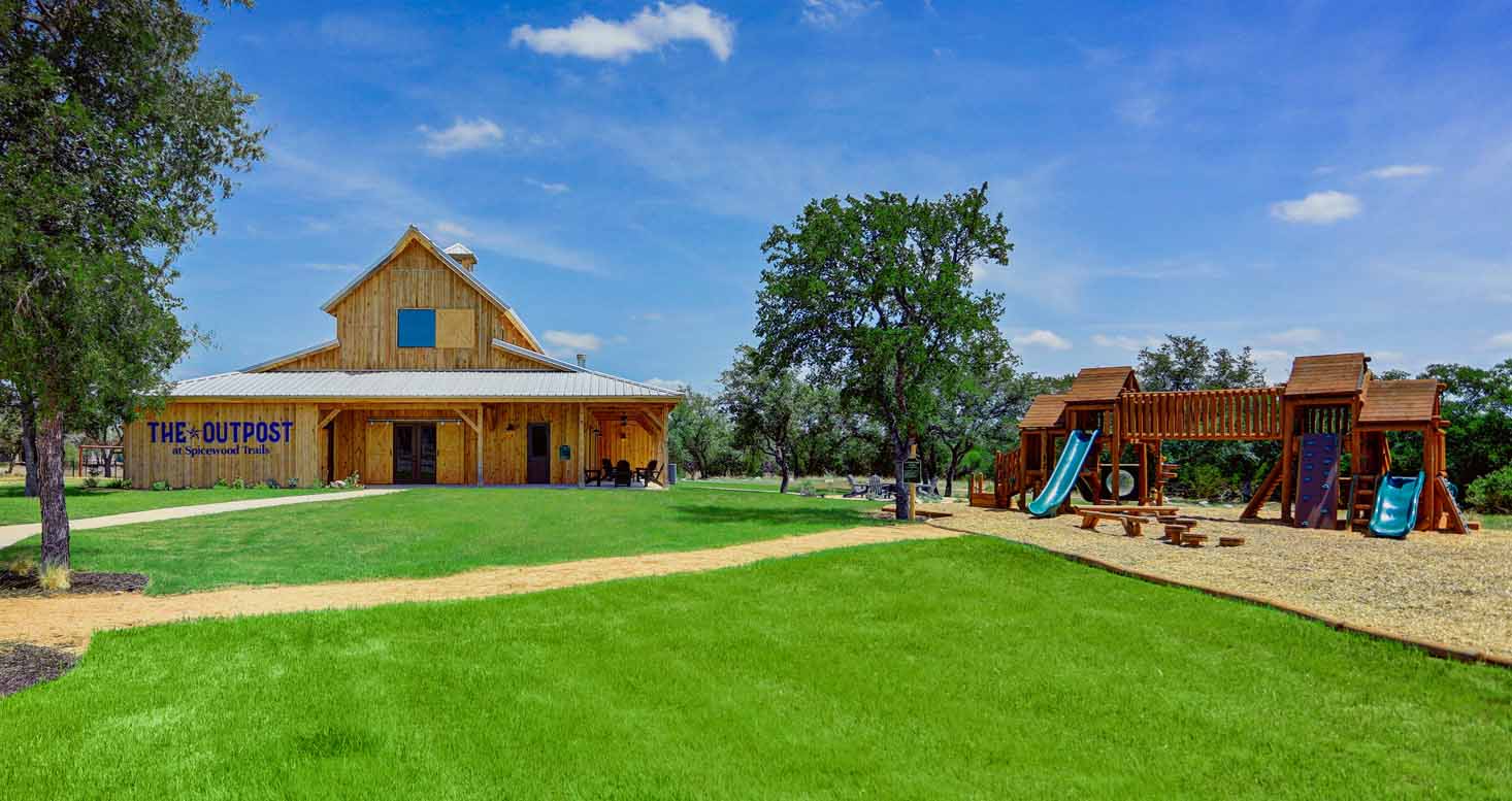 Large timber playset and swings beside a community gathering hall
